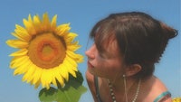 a woman is smelling a sunflower